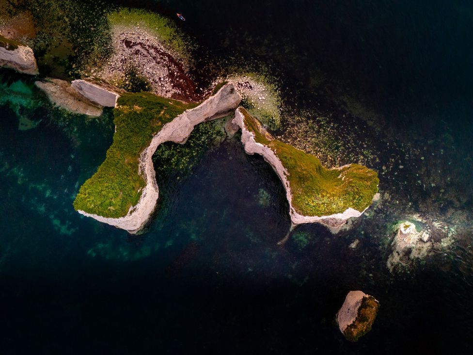 An aerial view of rock formations and greenery in the ocean at Seaheaven