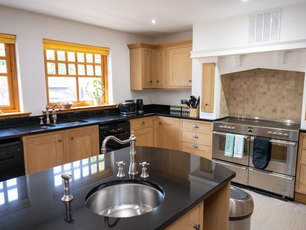 A kitchen with wooden cabinets and appliances at Old Distillery Lodge