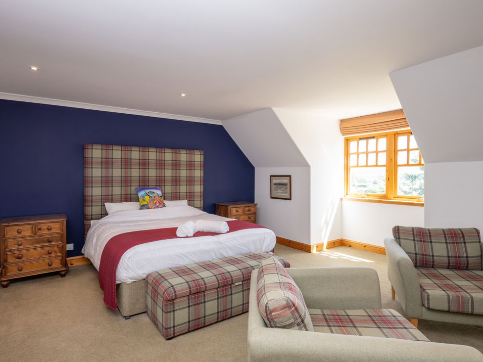 A bedroom with a bed and two armchairs at Old Distillery Lodge