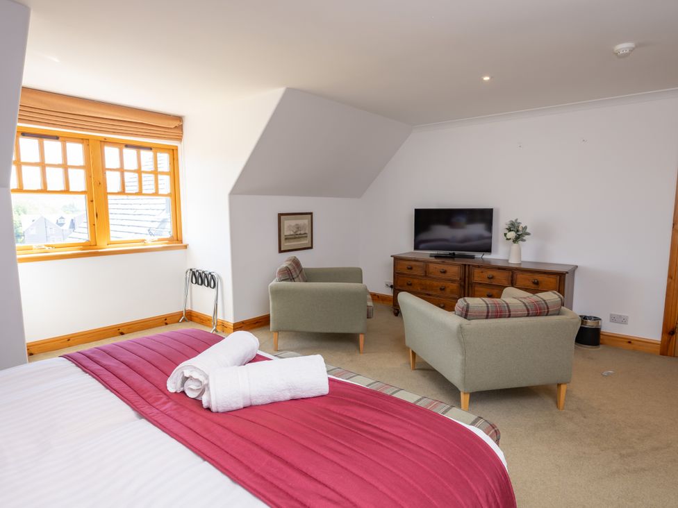 A bedroom with a bed and two armchairs at Old Distillery Lodge