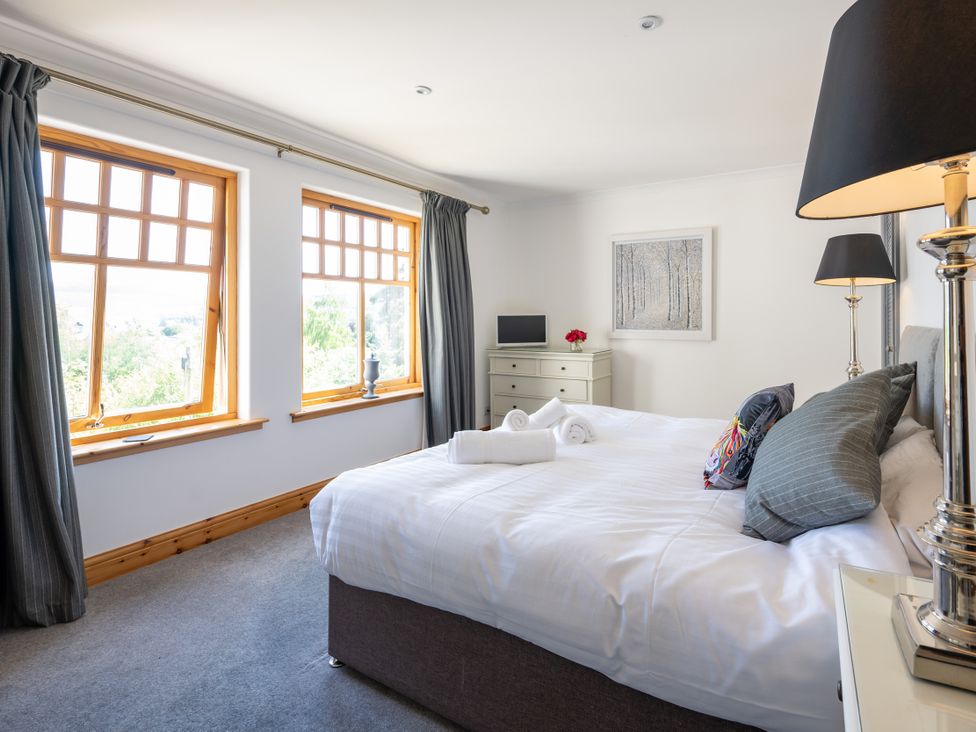 A bedroom with a bed and windows at Old Distillery Lodge