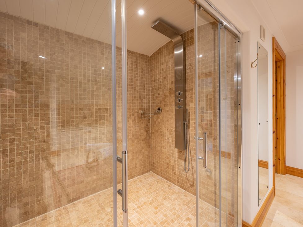 A shower with tiled walls and glass doors at Old Distillery Lodge