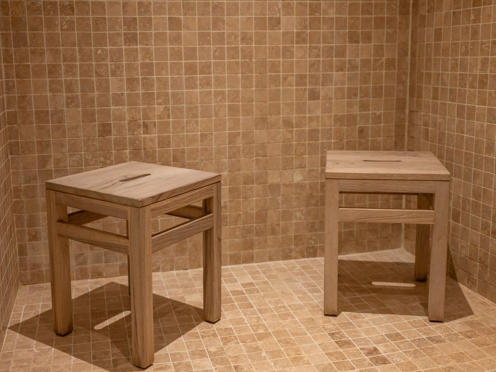 Two wooden stools in a bathroom with tiled walls and floor at Old Distillery Lodge