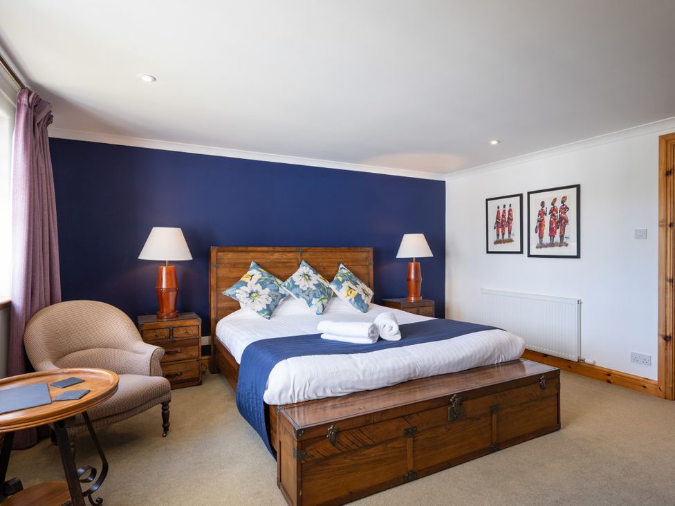 A bedroom with a bed and armchair at Old Distillery Lodge