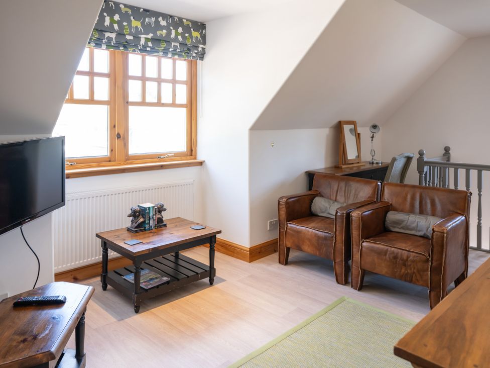 A living room with television and leather chairs at The Old Distillery Lodge 