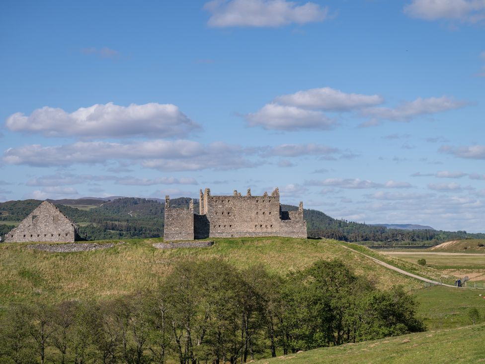 A castle ruin on a hill with greenery at the Old Distillery Lodge
