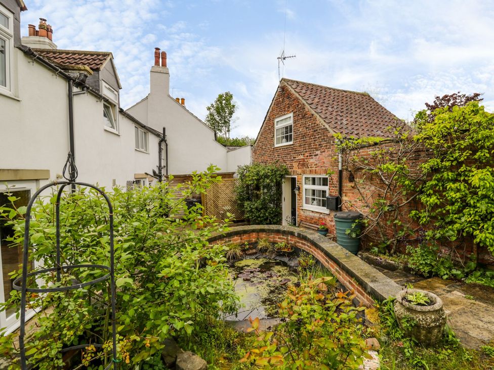 A garden with a pond and greenery at Figgy Cottage in Ripon