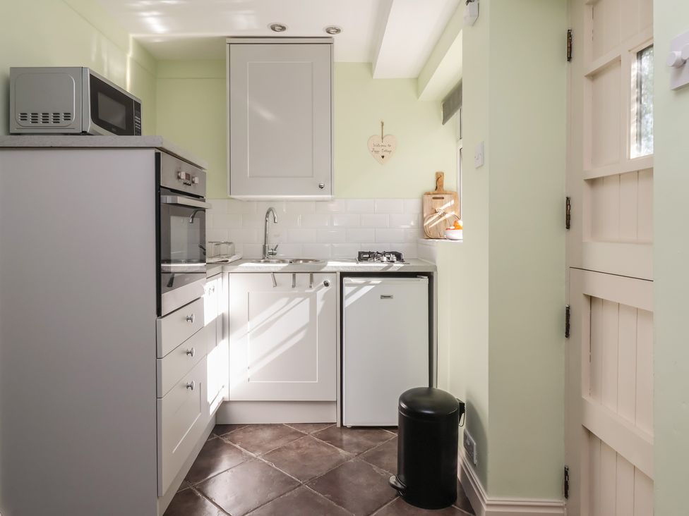 A kitchen showing a microwave, oven, sink, and refrigerator at Figgy Cottage in Ripon