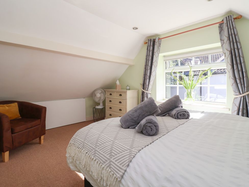 A bedroom with bed, towels and dresser at Figgy Cottage in Ripon