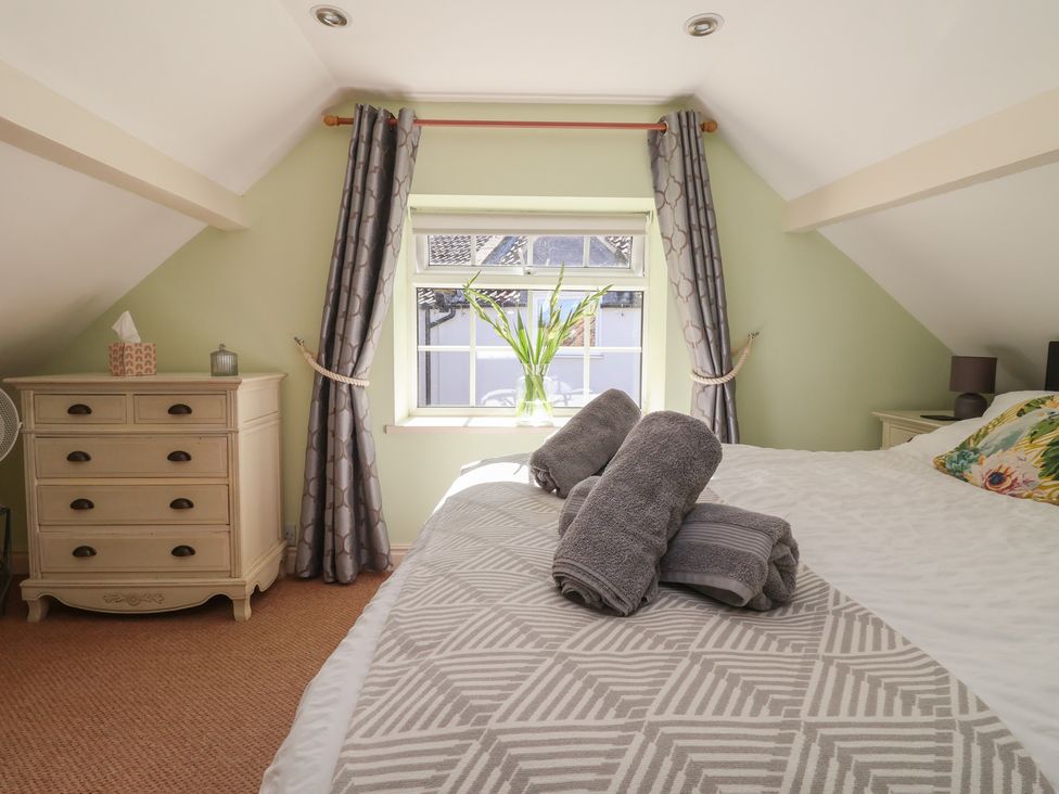 A bedroom with a bed and a dresser at Figgy Cottage in Ripon