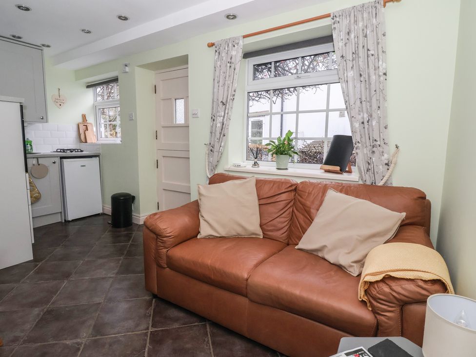 A living room with a sofa and kitchen area at Figgy Cottage in Ripon