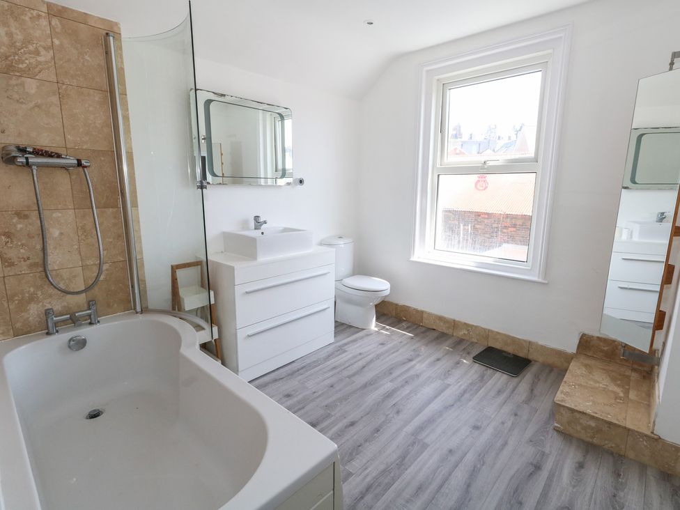 A bathroom with a bathtub, shower, toilet, and sink at Weymouth Seaside House in Weymouth
