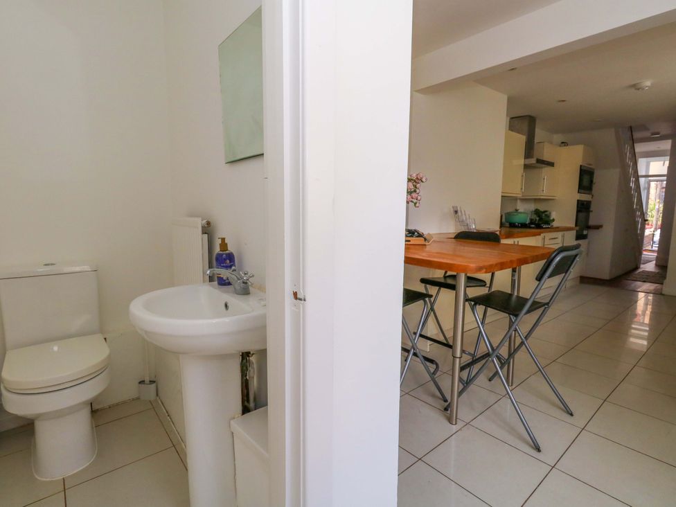 A bathroom with a sink and toilet beside a kitchen with a table at Weymouth Seaside House in Weymouth