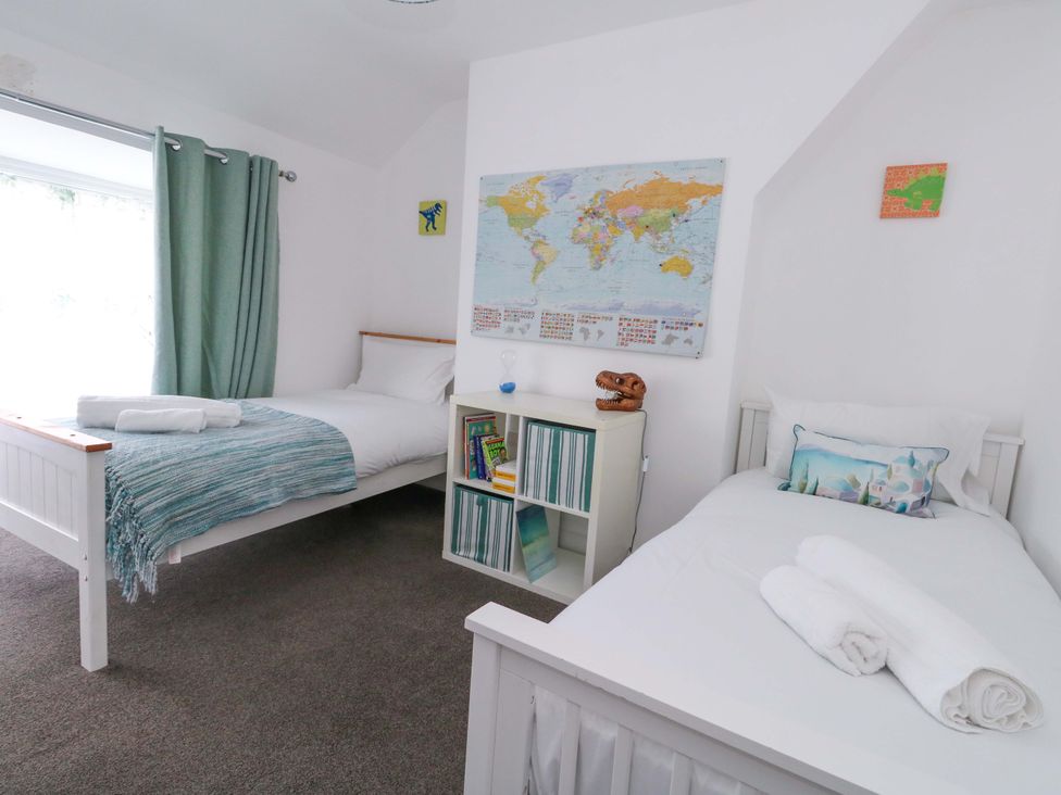 A bedroom with two beds and a world map on the wall at Weymouth Seaside House in Weymouth