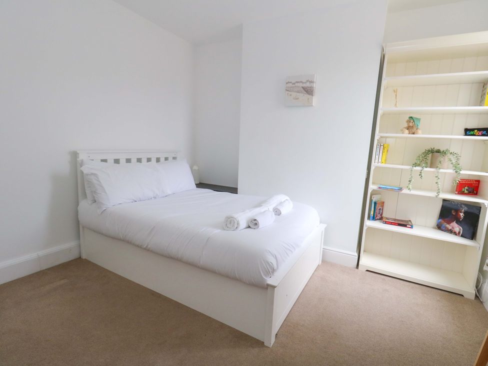A bedroom with a bed and shelves at Weymouth Seaside House in Weymouth