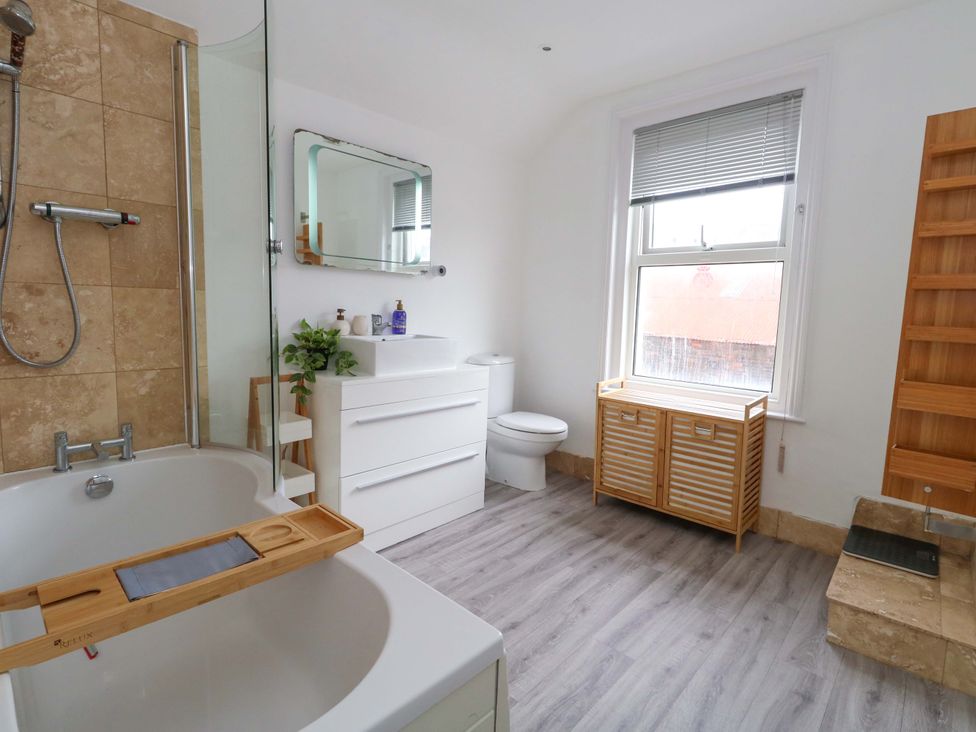 A bathroom with a bathtub, toilet, sink, and storage cabinet at Weymouth Seaside House, Weymouth
