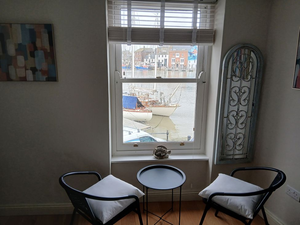 A living room with chairs and a table overlooking the harbor at Harbourside in Weymouth