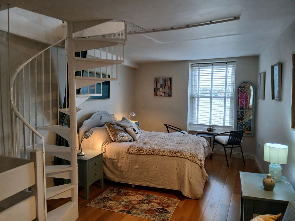 A bedroom with a bed and a spiral staircase at Harbourside in Weymouth