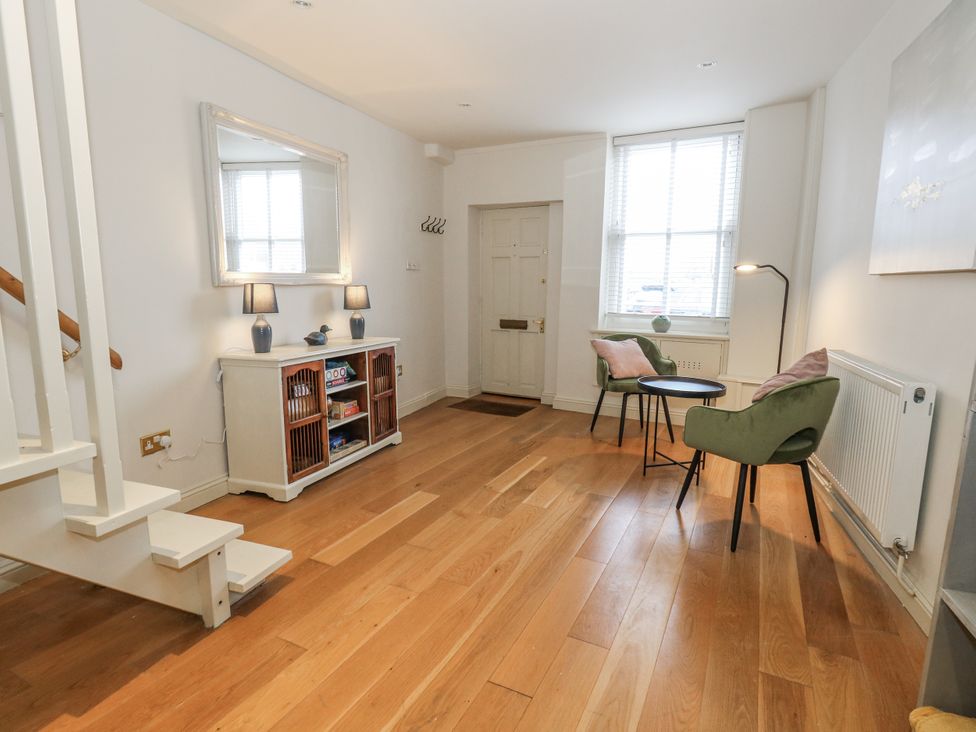 A hallway with a mirror, table, lamps, and a door at Harbourside in Weymouth