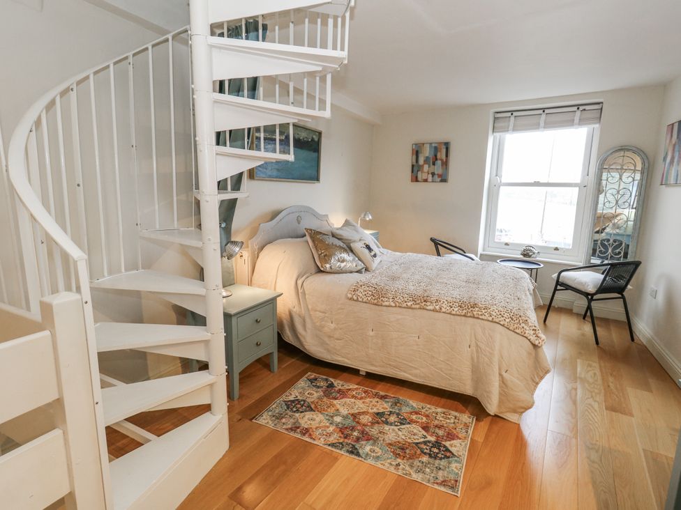 A bedroom with a spiral staircase and a bed at Harbourside in Weymouth