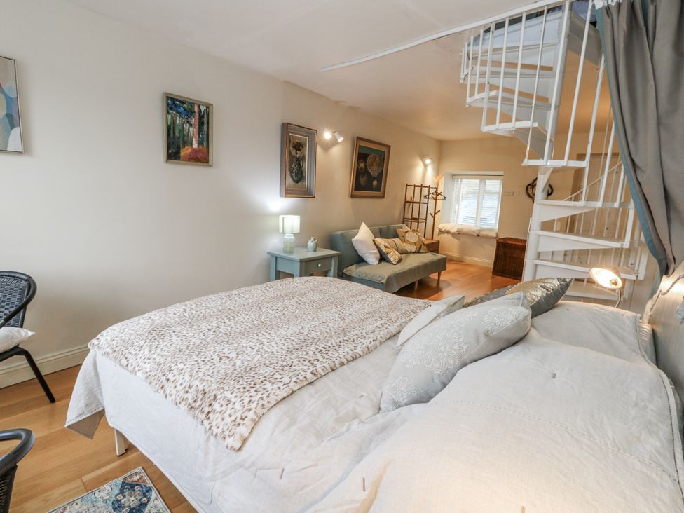 A bedroom with a bed, sofa, and staircase at Harbourside in Weymouth