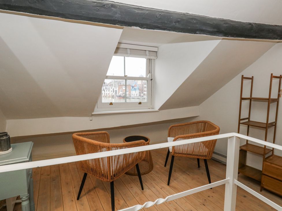 An attic with two chairs and a table at Harbourside in Weymouth
