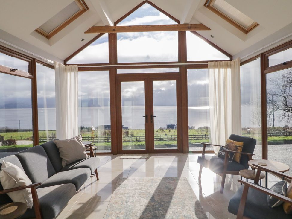 A conservatory with a sofa and armchairs overlooking a scenic view at Ard Na Mara in Drung near Quigley's Point, County Donegal