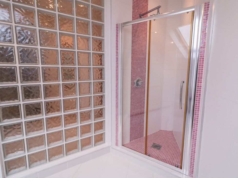 A shower enclosure with glass block wall and pink tiled floor at Ard Na Mara Drung near Quigley's Point, County Donegal
