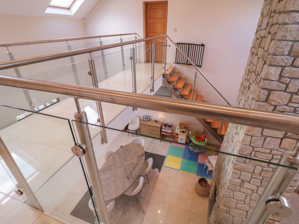 A staircase with glass railing overlooking a dining area at Ard Na Mara Drung near Quigley's Point, County Donegal
