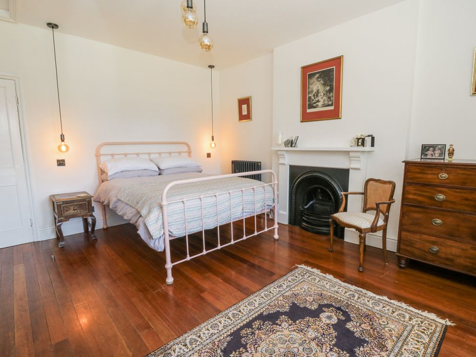 A bedroom with a bed, armchair, and fireplace at Glanrannell Park House in Llanwrda