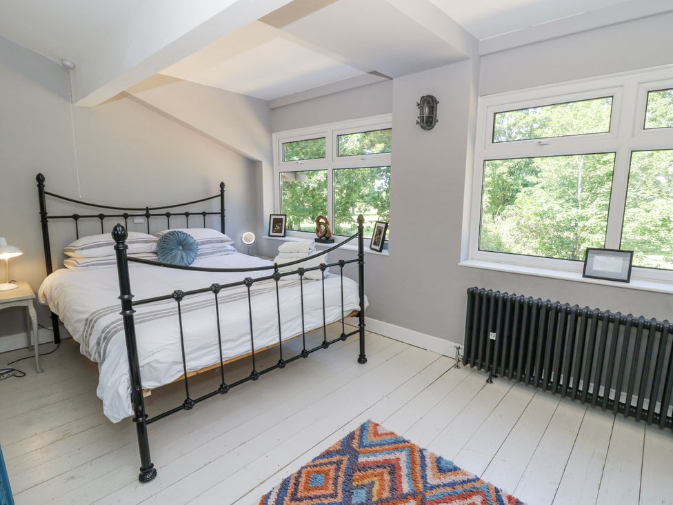 A bedroom with a bed and windows at Glanrannell Park House in Llanwrda