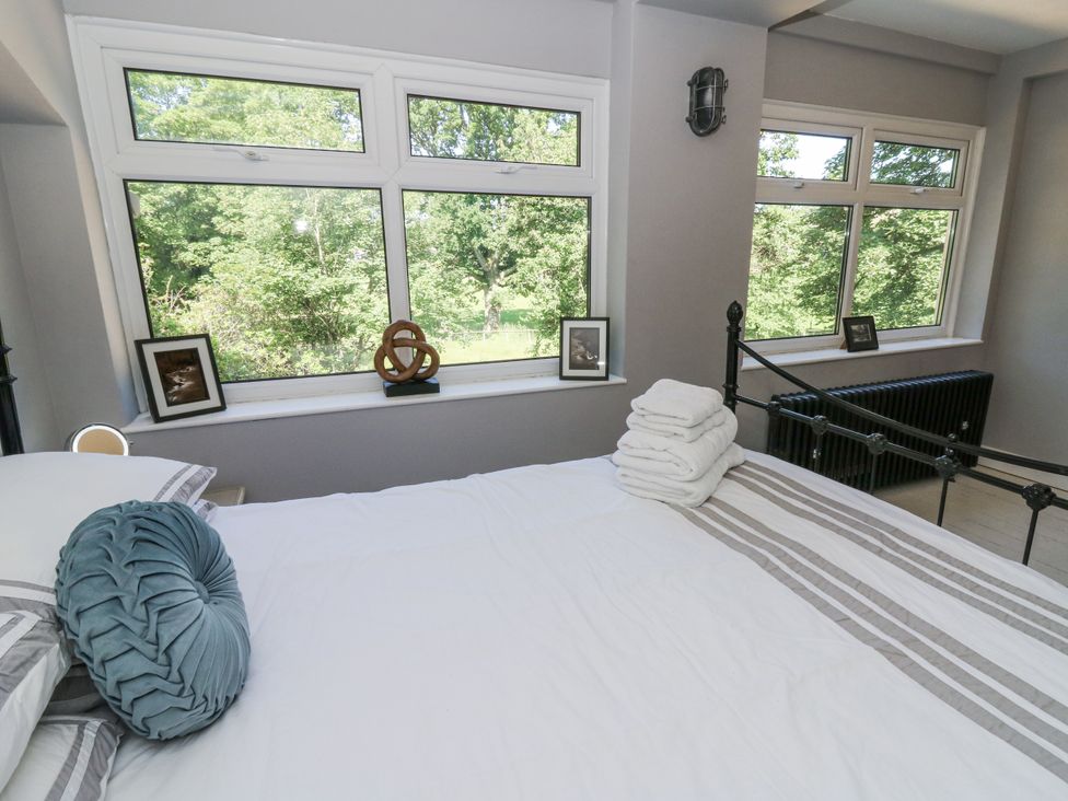 A bedroom with a bed and windows overlooking trees at Glanrannell Park House in Llanwrda