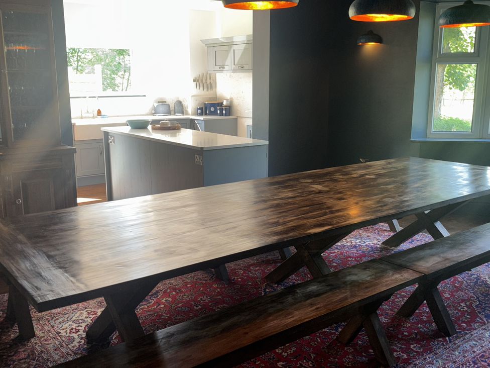A kitchen with a wooden table and benches at Glanrannell Park House Crugybar near Brechfa