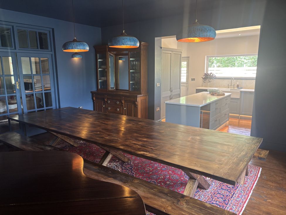 A dining room with a large wooden table and cabinet at Glanrannell Park House Crugybar near Brechfa