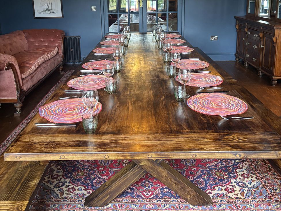 A dining room with a long dining table and chairs at The Retreat at Glanrannell Park House Llansawel