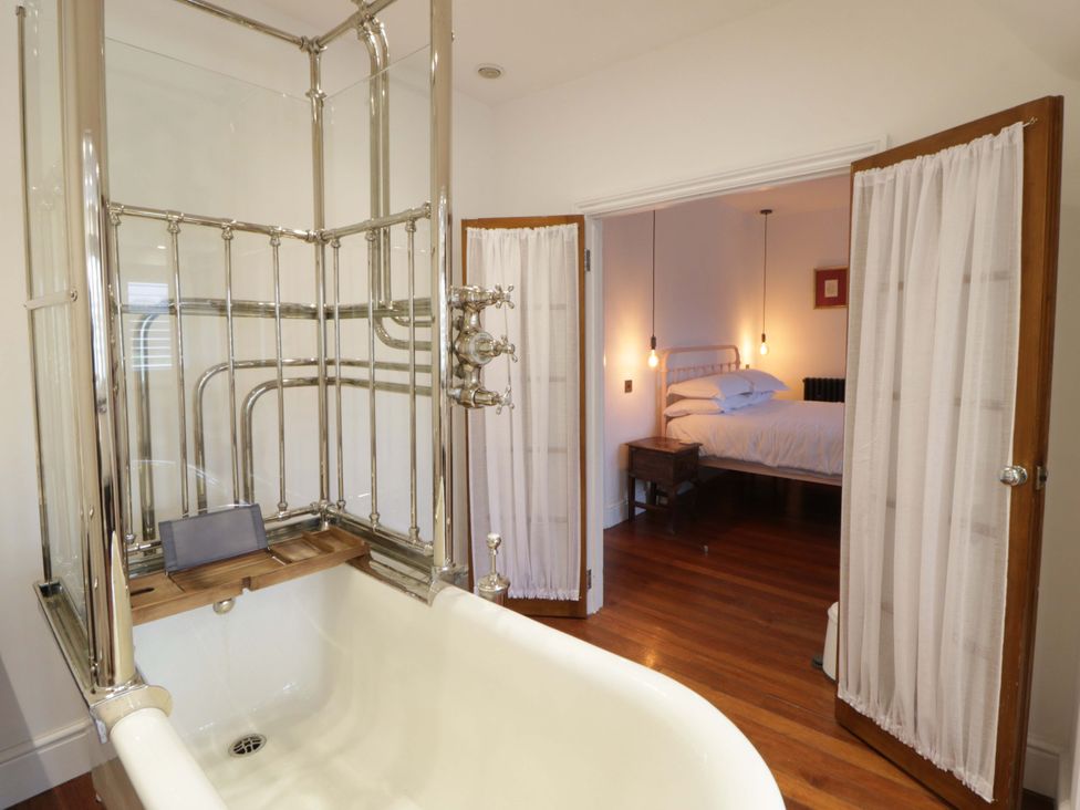 A bathroom with a bathtub and a view of a bedroom at The Retreat at Glanrannell Park House Llansawel