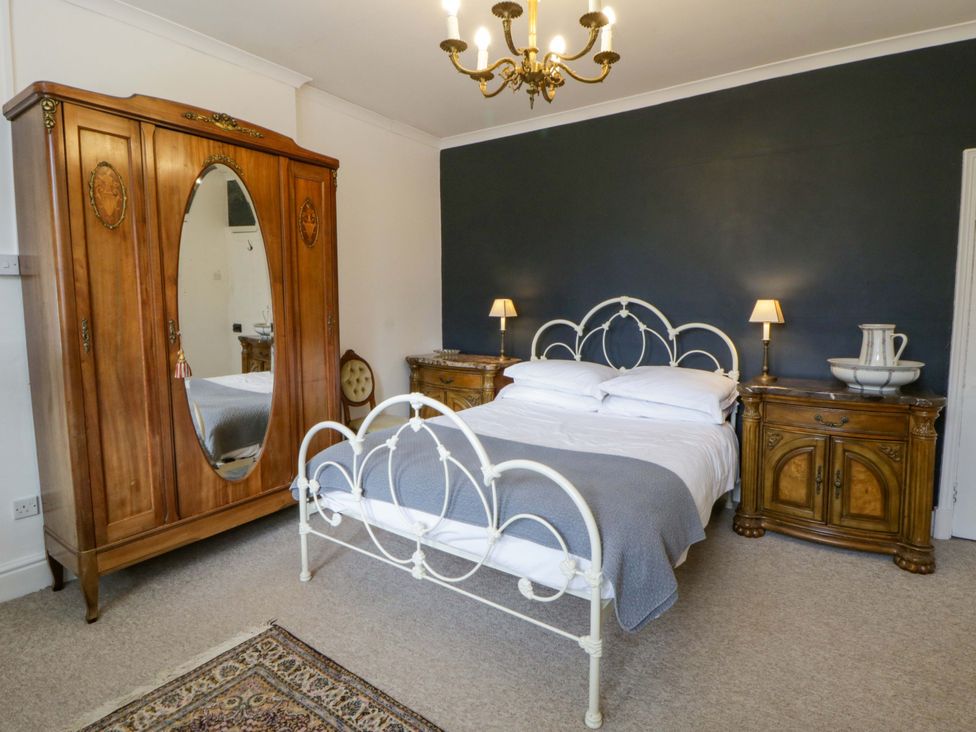A bedroom with a bed and wardrobe at The Retreat at Glanrannell Park House in Llansawel