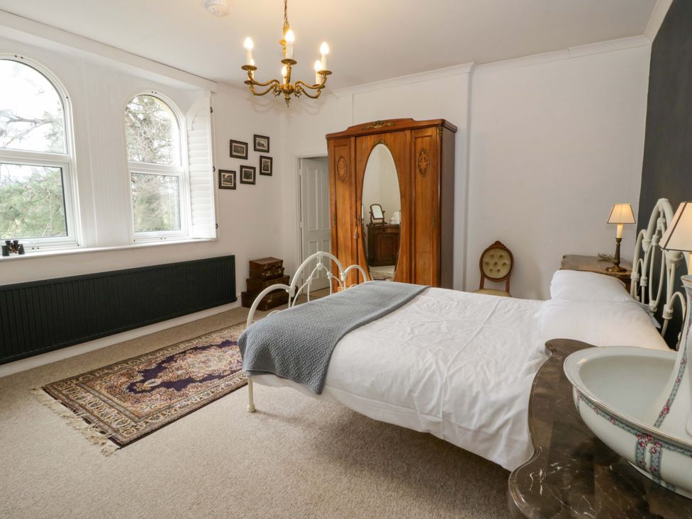 A bedroom with a bed and wardrobe at The Retreat at Glanrannell Park House in Llansawel