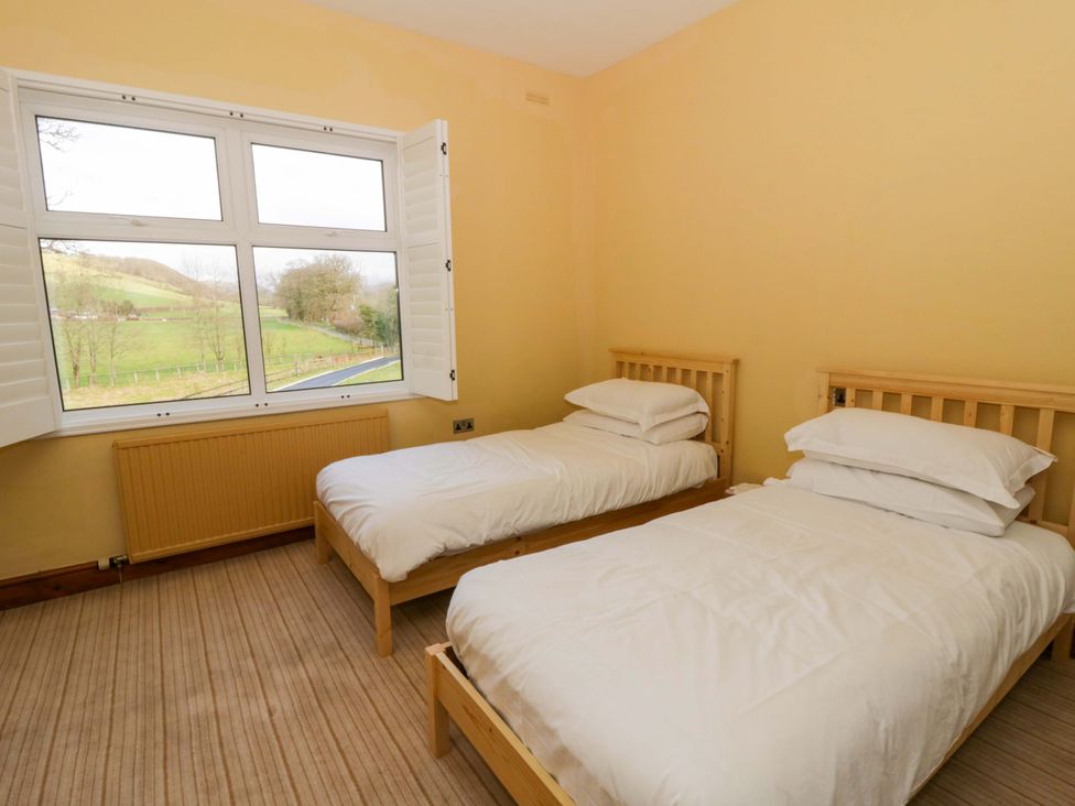 A bedroom with two single beds and a large window at The Retreat at Glanrannell Park House in Llansawel