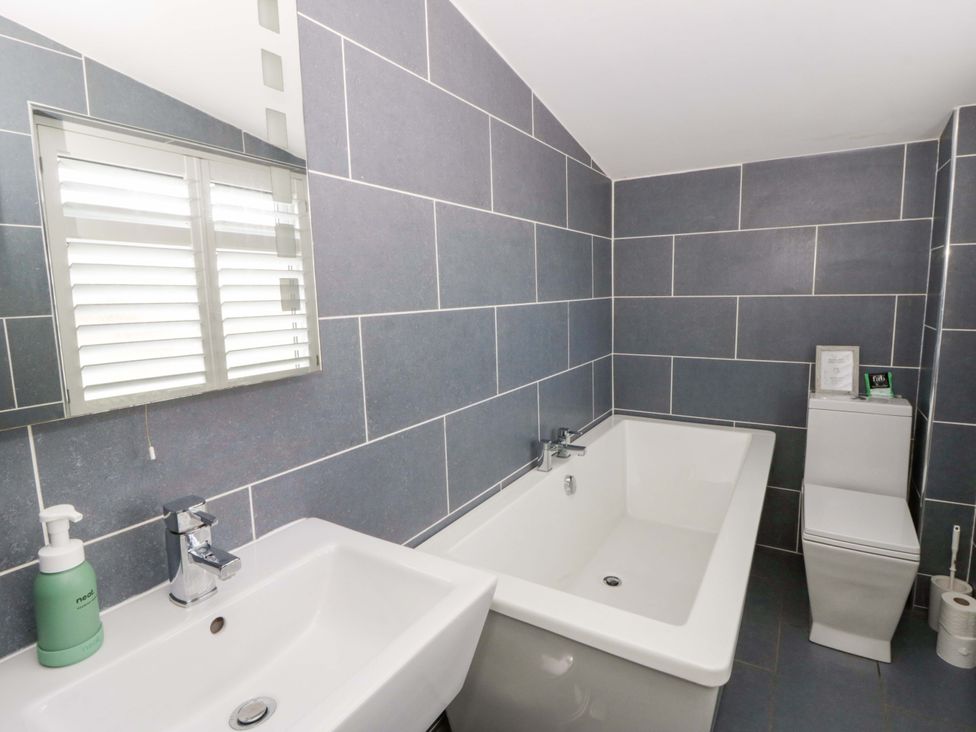 A bathroom with a bath tub and sink at The Retreat at Glanrannell Park House in Llansawel