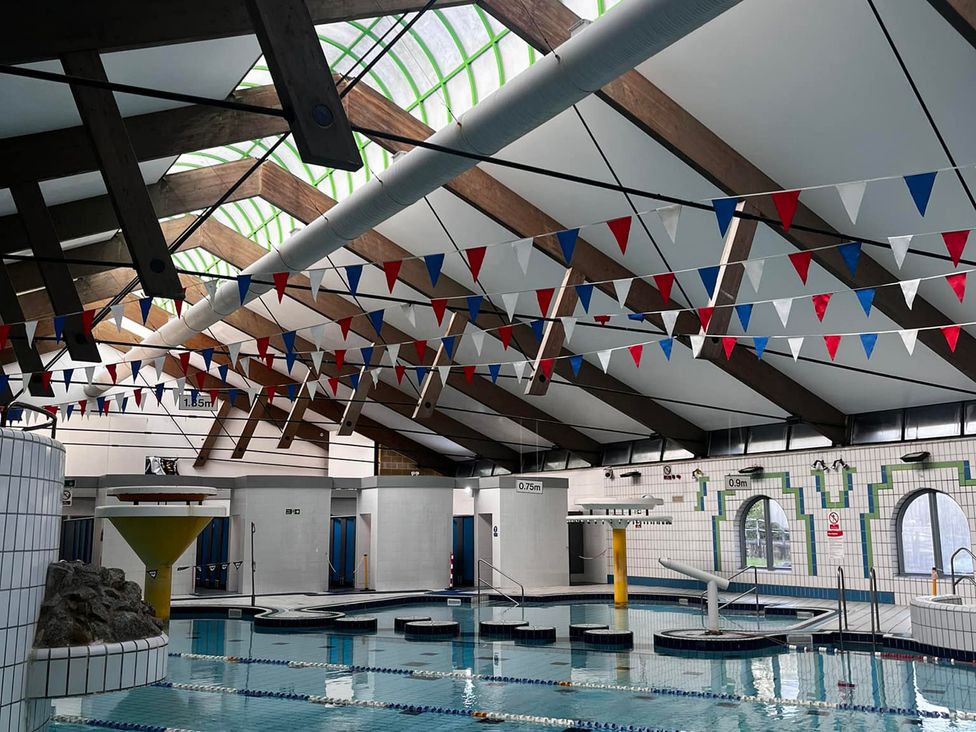 A swimming pool with diving board and banners at Valley Lodge 3, St Ann's Chapel, Cornwall