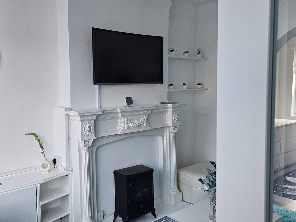 A living room with a fireplace and television at Anfield Stadium House in Liverpool