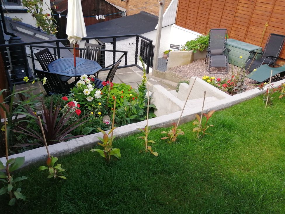 A garden with furniture and flowers at Colliers Cottage in Cinderford