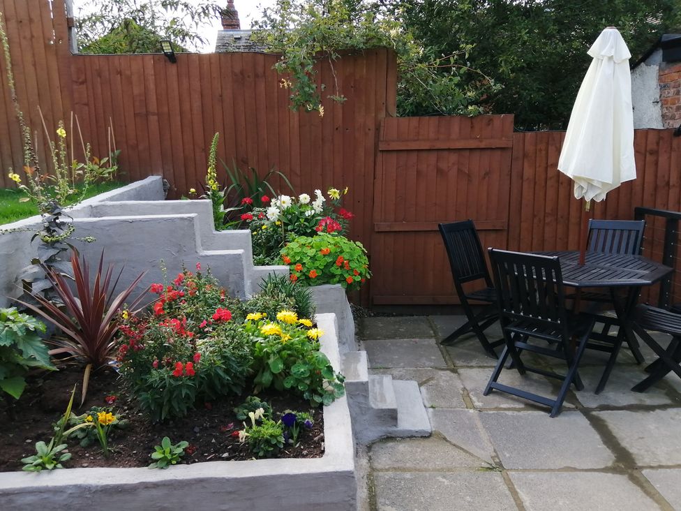A garden with flower beds and seating area at Colliers Cottage in Cinderford
