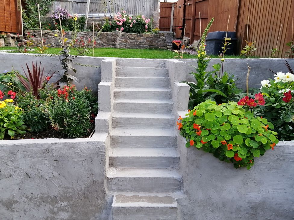 A garden with stairs and flower beds at Colliers Cottage in Cinderford