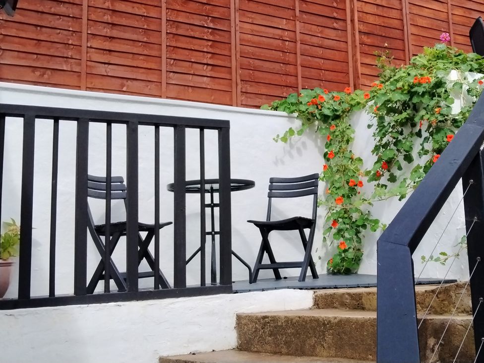 An outdoor seating area with a table and chairs at Colliers Cottage in Cinderford
