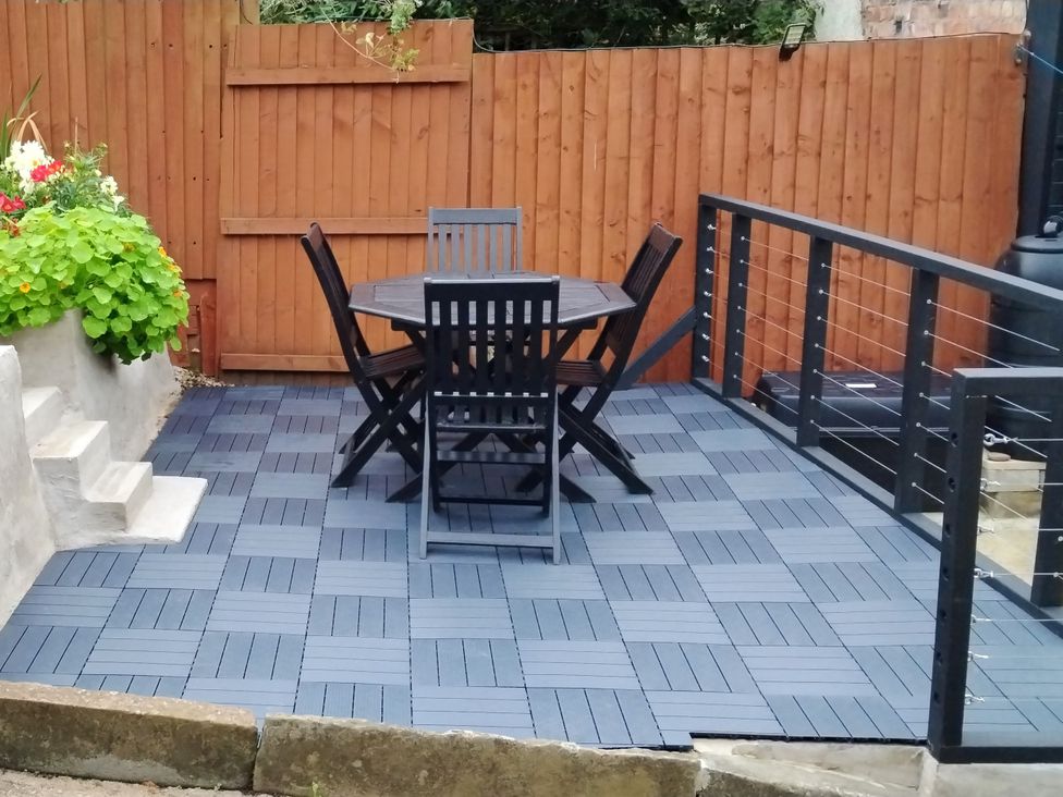 A garden with a table and chairs on a wooden deck at Colliers Cottage in Cinderford
