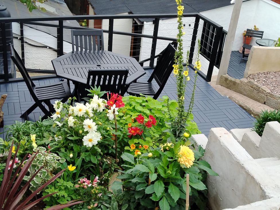 A garden with table and chairs surrounded by flowers at Colliers Cottage in Cinderford