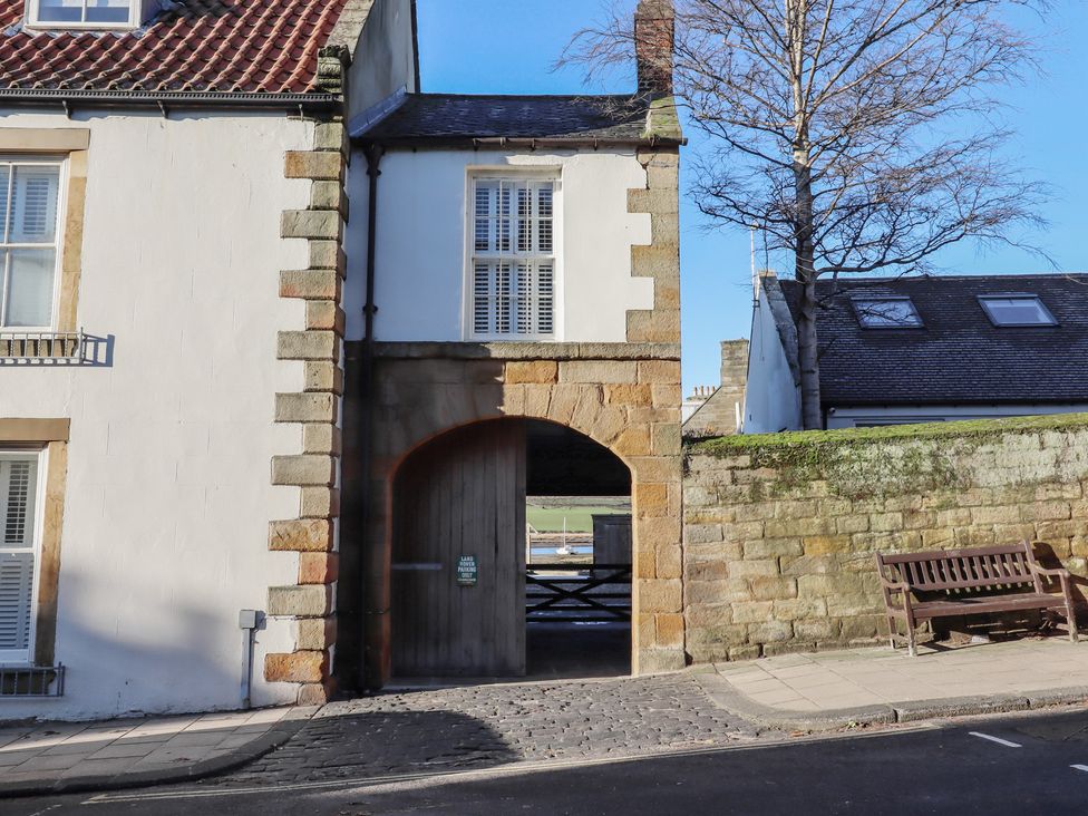 An archway leading through a wall with a bench outside at Seafield Granary, Alnmouth