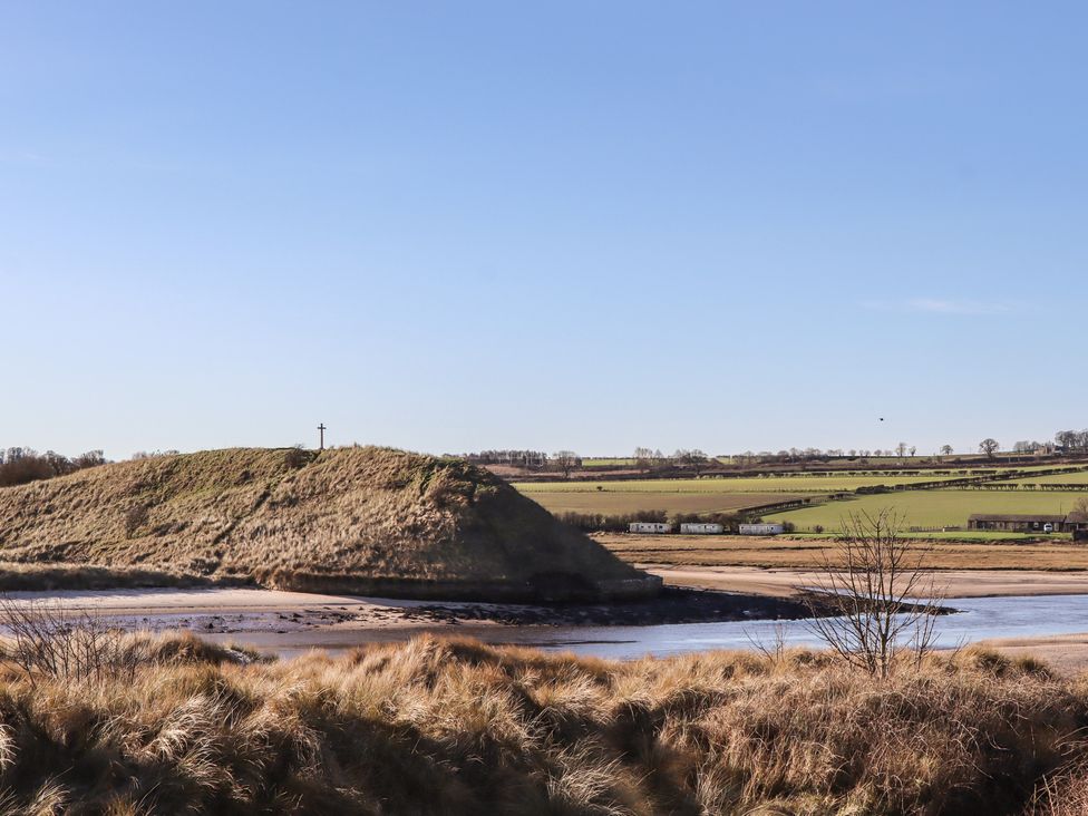A view with a hill and cross near water at Seafield Granary Alnmouth